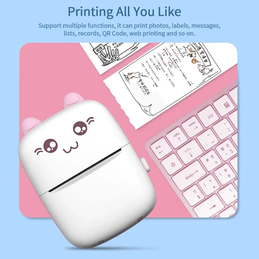 Small printer with cartoon face on a pink keyboard and mouse pad