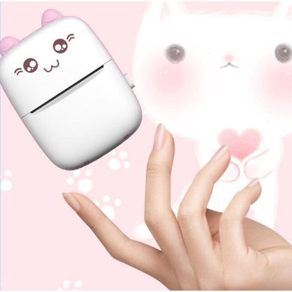 Cute white device with cartoon face held by a hand against a pink background