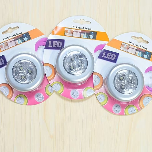 Three LED touch lamps in their packaging on a wooden surface