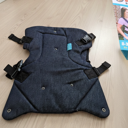 Dark blue baby carrier with straps on a light wooden surface