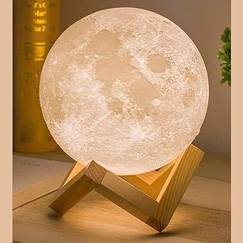Moon-shaped lamp with wooden stand on a wooden surface