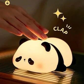 Panda-shaped night light being clapped by a hand on a reflective surface.